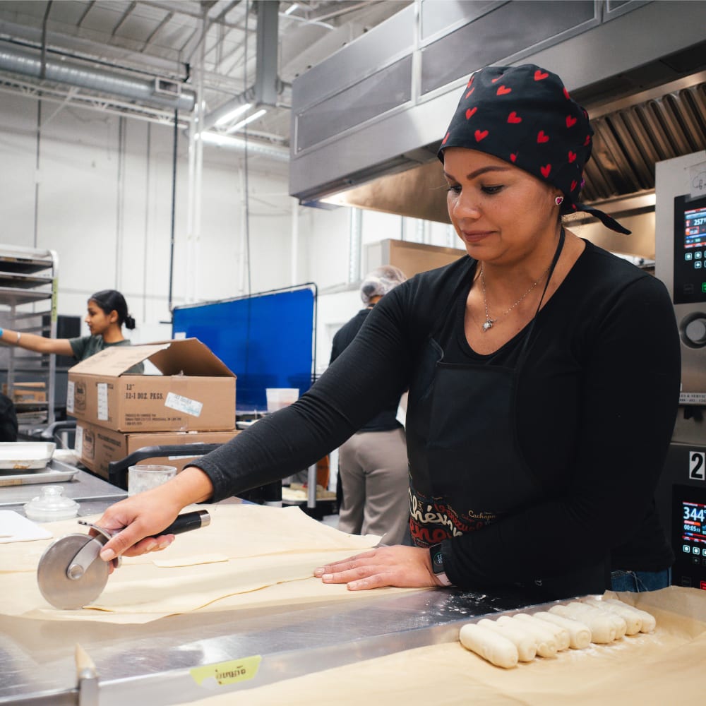 A worker slices dough at YVR Prep